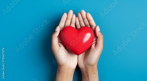 The essence of love with hands presenting a red heart on a serene blue background, an eloquent symbol of affection. Generative AI. photo
