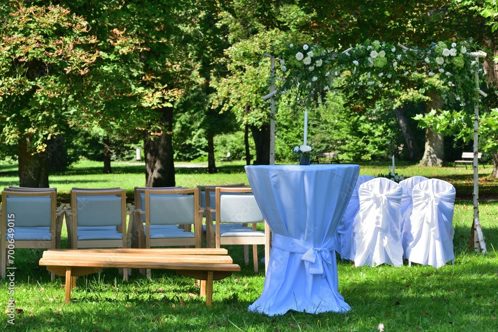 Decorated wedding altar at an outdoor wedding in a garden park with white chairs