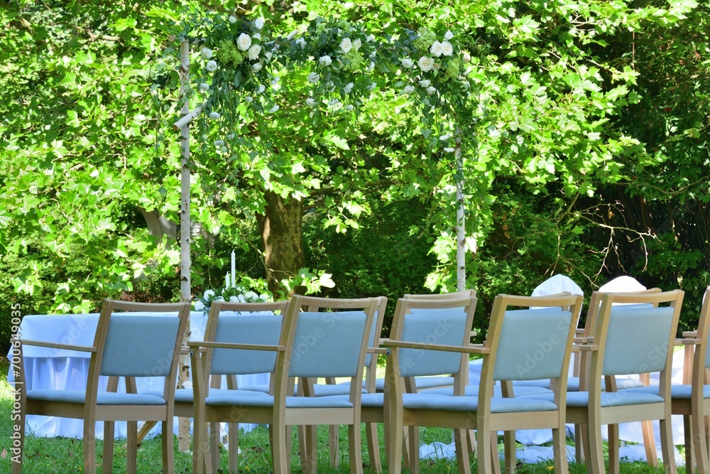 White decorated wedding chairs for guests in a garden park for a wedding