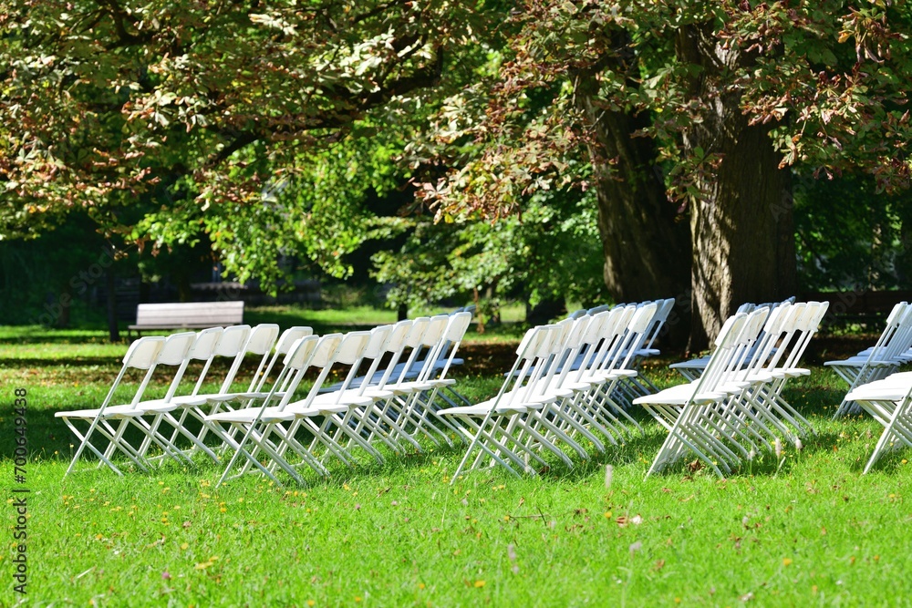 White decorated wedding chairs for guests in a garden park for a wedding