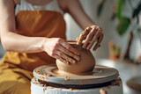close up hands of a young woman potter modeling ceramic pot from clay on a potter wheel at a modern house. Lifestyle concept of workshop and culture.