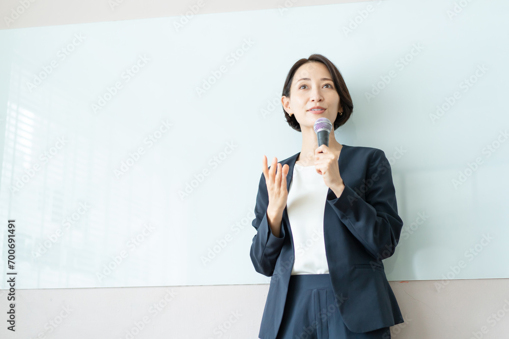 マイクを使ってプレゼンテーションを行う女性 マイクを使ってプレゼンテーションを行う女性