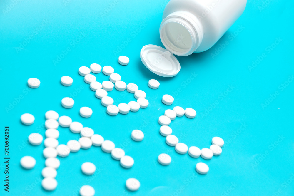 White tablets near the pharmacy jar in the shape of the letters ABC. White tablets near the pharmacy jar in the shape of the letters ABC.