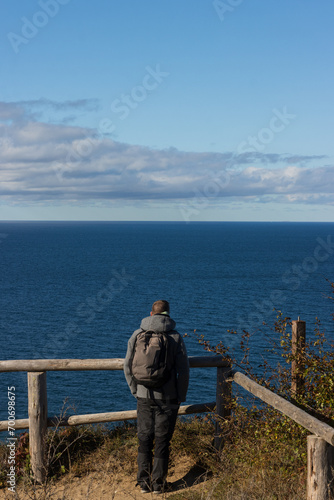 Back view of a man with backpack looking out on the sea.