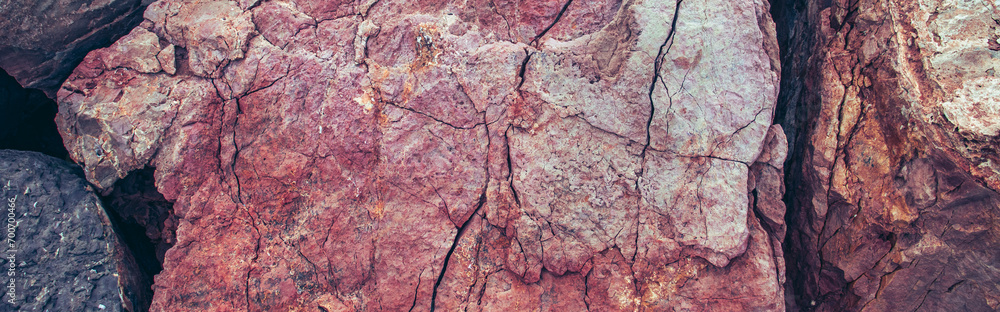 The surface of the mountain stone wall photo. Rock texture. Pink grunge background near seaside. The surface of the mountain stone wall photo. Rock texture. Pink grunge background near seaside.