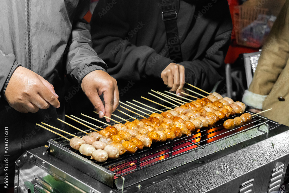 Naklejka premium Northeastern Sausage,Thai street food. Thai sausage grilled on stall. Sai Krok Isaan or Pork sausage with rice grill. Made of pork and spiced with garlic and white peppercorns. Isaan sausage.