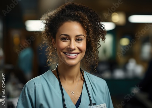 A joyful woman, adorned with a stethoscope and a delicate necklace, exudes confidence and professionalism in her stylish scrubs as she graces us with a warm smile inside