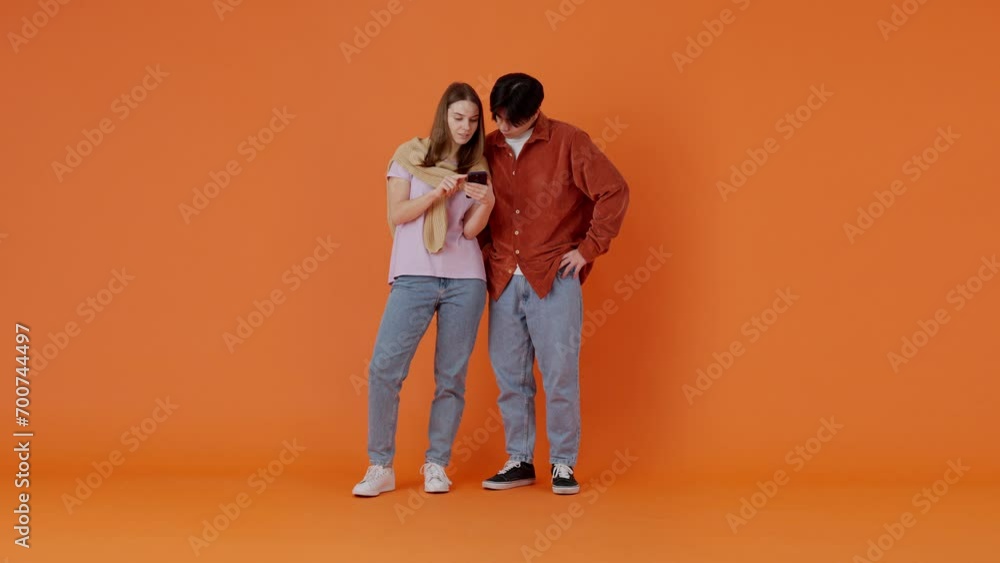 Woman and Asian man winning game on mobile phone in studio Woman and Asian man winning game on mobile phone in studio