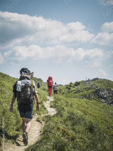 Group of adult backpacker hiker persons walking through a mountain meadow in summer, Fatra Fatry Moundains
