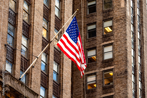 The beautiful big American flag flying on the skyscraper buildings of the Manhattan district in the Big Apple, symbol of New York City.