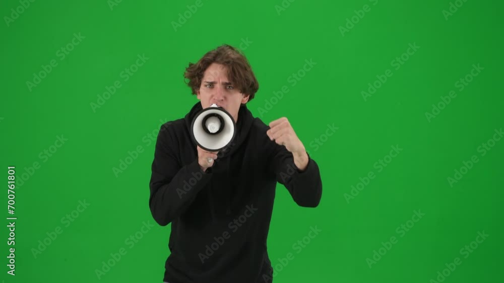 Male activist with raised fist shouting menacingly into megaphone in studio on green screen. Front view of a pro protest man close up. Protest action, fight for human rights, strike. Male activist with raised fist shouting menacingly into megaphone in studio on green screen. Front view of a pro protest man close up. Protest action, fight for human rights, strike.