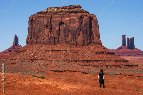 A women dressed in black admiring the rock formations in Monument valley, Utah, USA. Blue sky and bright daylight. Orange rocks, spring time.