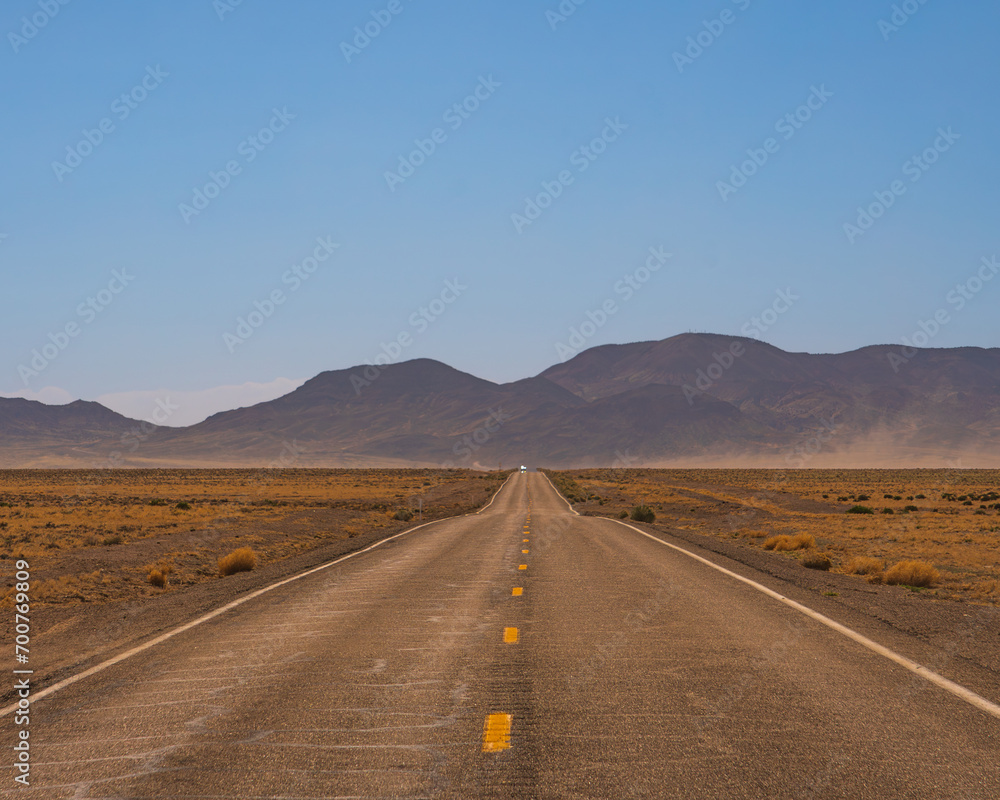 a lonely road (state road 375) in southwestern USA, in Nevada near area 51, dry arid desert landscape and bright light.