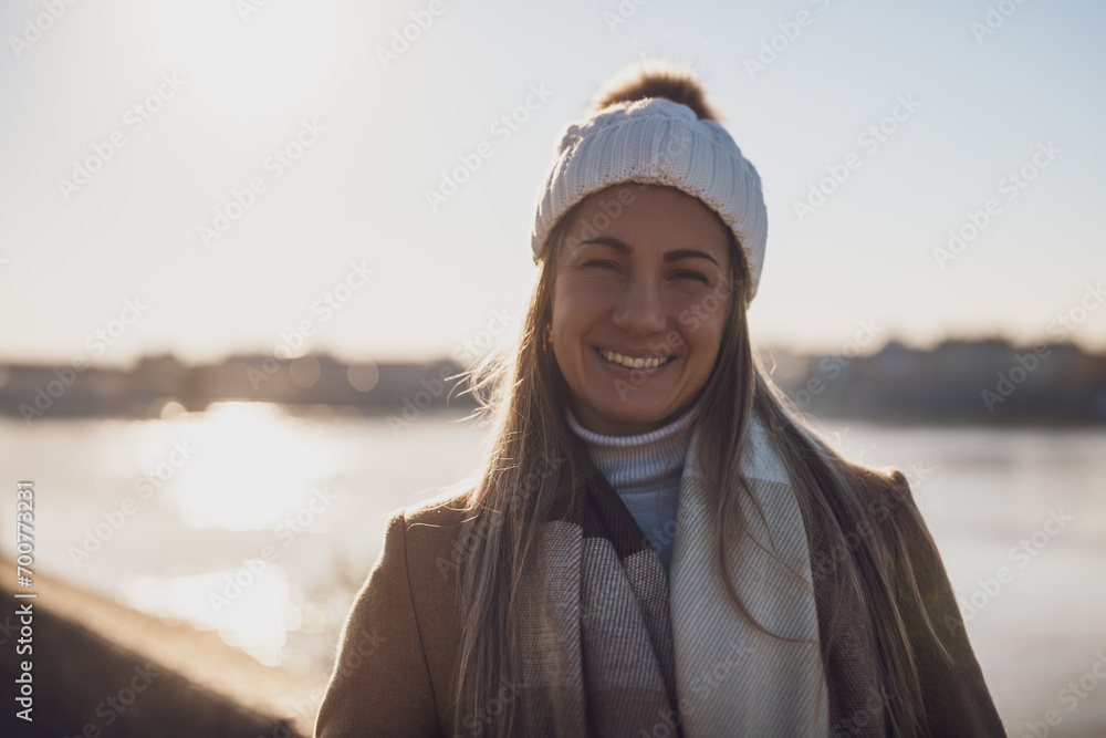 Close up portrait of natural beautiful woman in warm clothing enjoys spending time by the river on a sunny winter day. Toned image. Close up portrait of natural beautiful woman in warm clothing enjoys spending time by the river on a sunny winter day. Toned image.