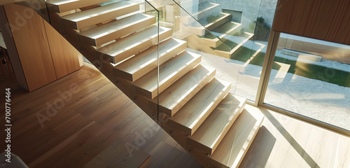 A chic, light oak staircase with glass sides, creating a visual connection between floors in a stylish, airy interior.