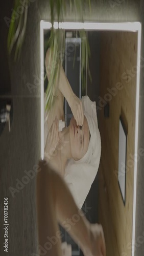 Caucasian female in her 40s is making her daily skin care routine