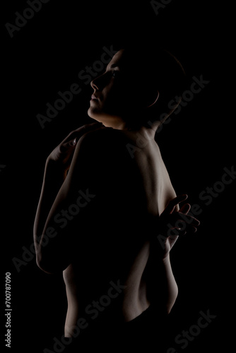 Portrait of a girl with short hair against dark background. Side lit contour slhouette of a female body.. photo