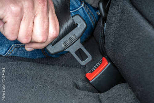 Close up of hand fastening seat belt buckle. Safety driving in car traveling. photo