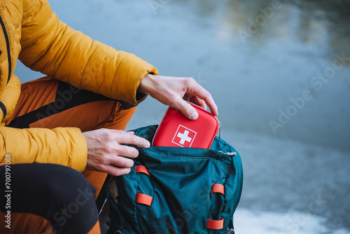 A guy puts a first aid kit in a backpack, packing things for a hike, safety in a winter trip, trekking in the mountains. personal first aid kit. photo