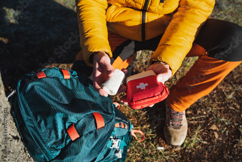 First aid kit in the hands of a man on a hike, a roll of elastic bandage, first aid in the mountains, survival in the forest. photo