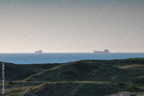 View on a dune landscape with two ships at anchorage in the horizon