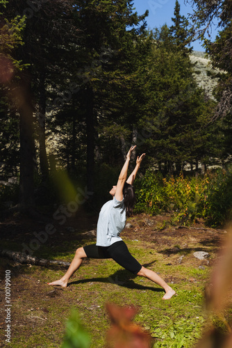 Girl practicing yoga in nature in the forest, healthy lifestyle, body care, flexible mind, workout in the park side view, woman standing barefoot on the grass.
