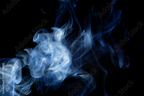 Abstract blue smoke swirling and dancing against a stark black background