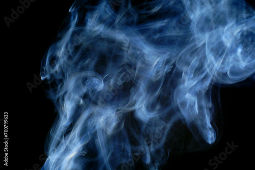 Cuadro en lienzo Abstract blue smoke swirling and dancing against a stark black background
