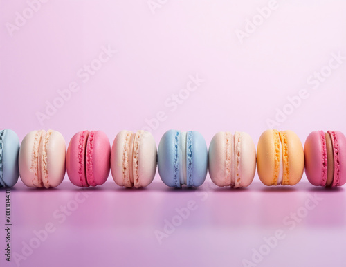 a row of colorful macarons in pastel shades of blue, pink, and yellow, arranged neatly against a soft pink background, creating a delightful and appetizing visual. 