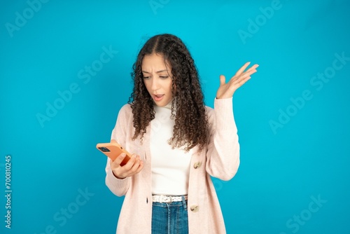 Angry beautiful teen girl wearing brown cardigan screaming on the phone, having an argument with an employee. Troubles at work.