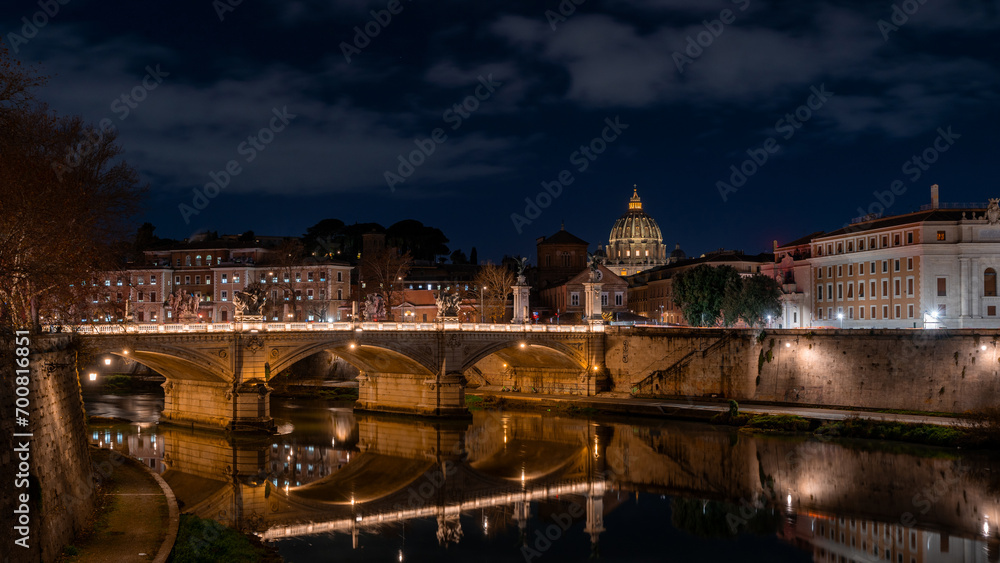 Night view of the Vittorio Emanuele bridge and the dome of San Pietro reflected in the Tiber river