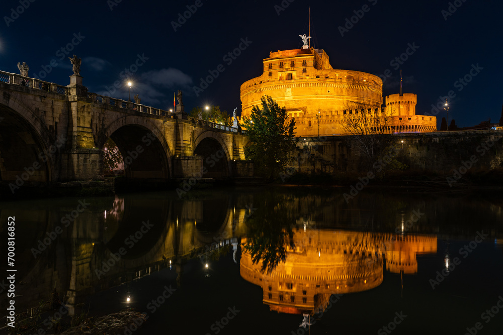 Night view of the Castel Sant'Angelo fortress and the Sant'Angelo bridge reflected in the Tiber river