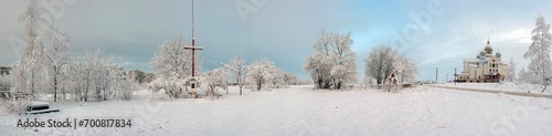 Panorama of a beautiful church and cross under deep snow on a beautiful winter day.