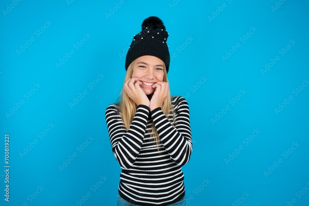 Fearful Teen caucasian girl wearing striped sweater and woolly hat keeps hands near mouth, feels frightened and scared,  has a phobia,  Shock and frighted concept.