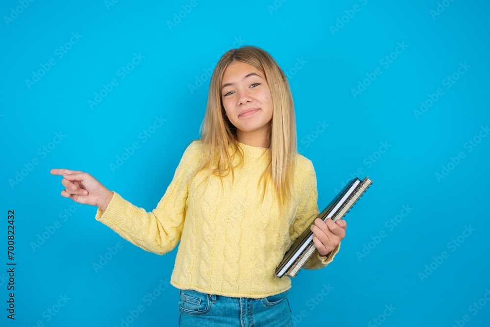 beautiful caucasian teen girl wearing yellow sweater points to side on blank space demonstrates advertisement. People and promotion concept beautiful caucasian teen girl wearing yellow sweater points to side on blank space demonstrates advertisement. People and promotion concept