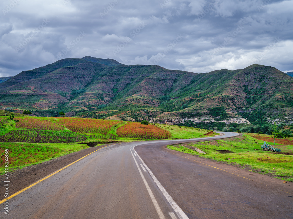 Winding road through lush Lesotho with agricultural land and mountain surrounding the valley