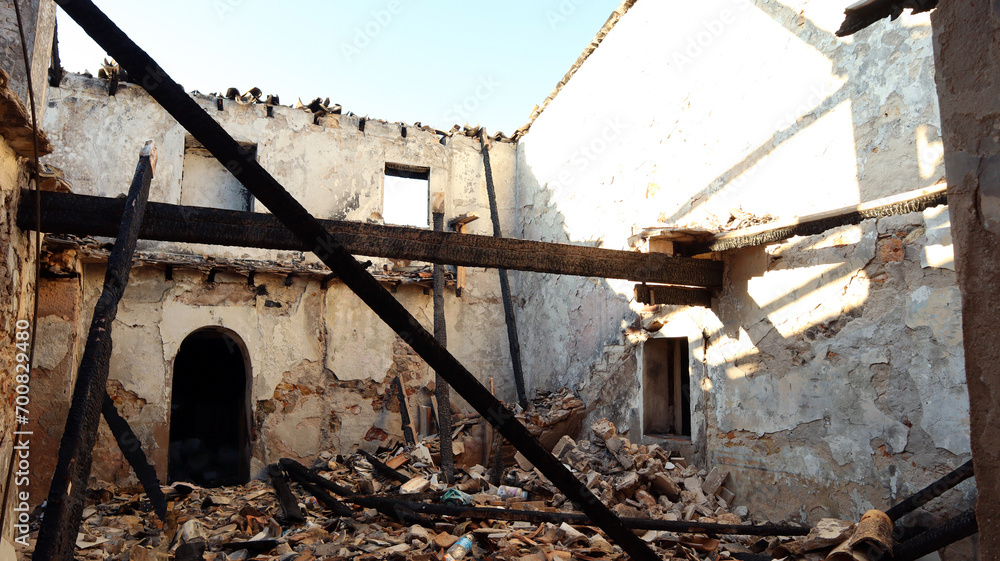 Ruins of a house after a fire, burnt house, charred ceilings, destroyed walls, garbage 