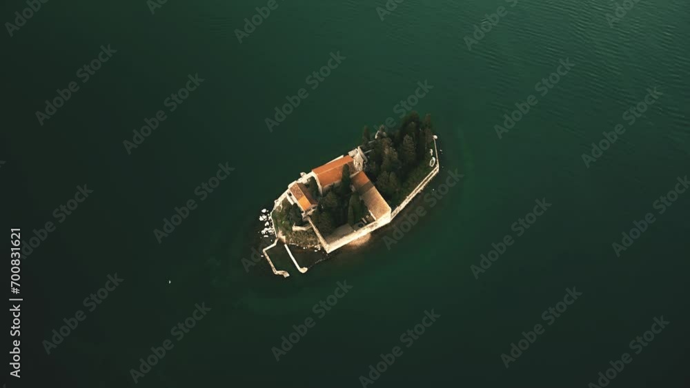 Aerial orbiting shot of an old tiled church on a small secluded islet. Isolation and retreat concepts. Montenegro Aerial orbiting shot of an old tiled church on a small secluded islet. Isolation and retreat concepts. Montenegro