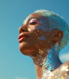 A woman gazes up at the sky, her human face adorned with shimmering glitter as she blows a bubble in the beautiful blue water, embracing the freedom and joy of being outdoors
