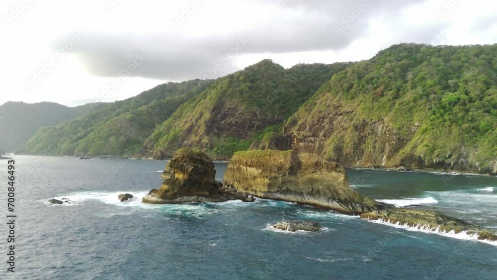 Drone shot on Papuma Beach, Jember, Indonesia with thick vegetations, towering cliff and ocean waves. Drone shot on Papuma Beach, Jember, Indonesia with thick vegetations, towering cliff and ocean waves.