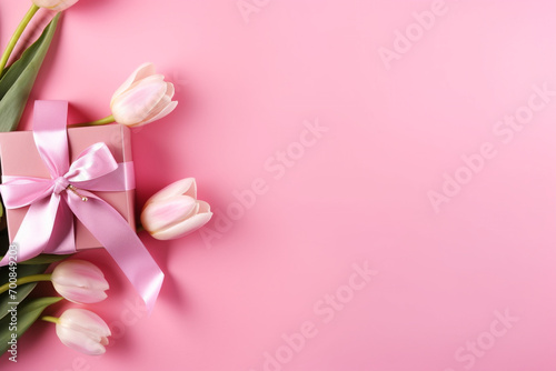 Mother s Day concept. Top view photo of stylish pink giftbox with ribbon bow and bouquet of tulips on isolated pastel pink background with copyspace