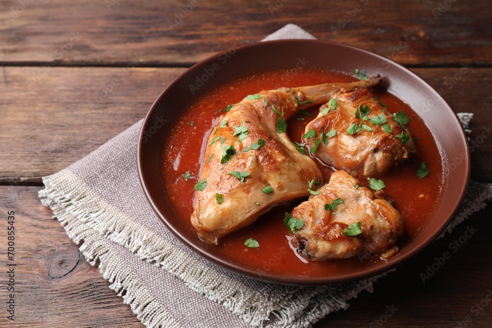 Tasty cooked rabbit meat with sauce and parsley on wooden table Tasty cooked rabbit meat with sauce and parsley on wooden table