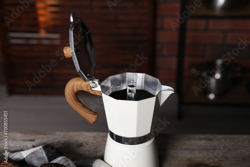 Aromatic coffee in moka pot on wooden table, closeup photo