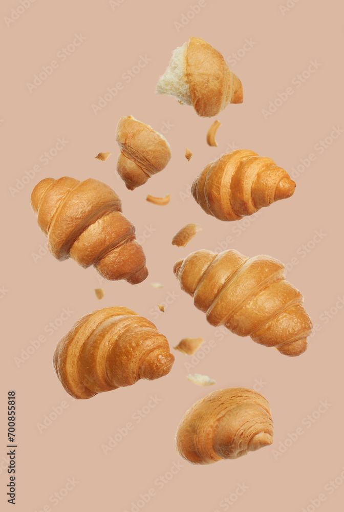 Delicious fresh croissants falling on beige background
