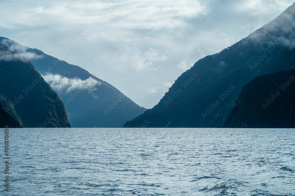 Photograph of low hanging clouds over mountains in Milford Sound in Fiordland National Park on the South Island of New Zealand