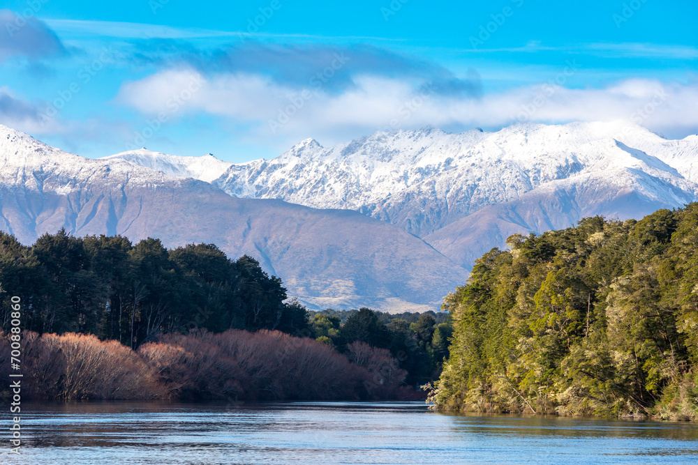 Fototapeta premium Photograph of snow capped mountains and flood waters in the Waiau River at the Manapouri Boat Club in Fiordland on the South Island of New Zealand