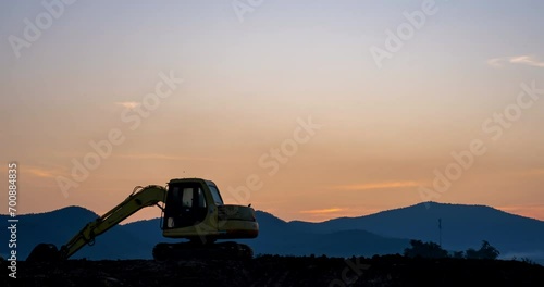 Time-lapse of a Silhouette Backhoe in a construction site from dawn to sunrise with dolly-in shot. photo