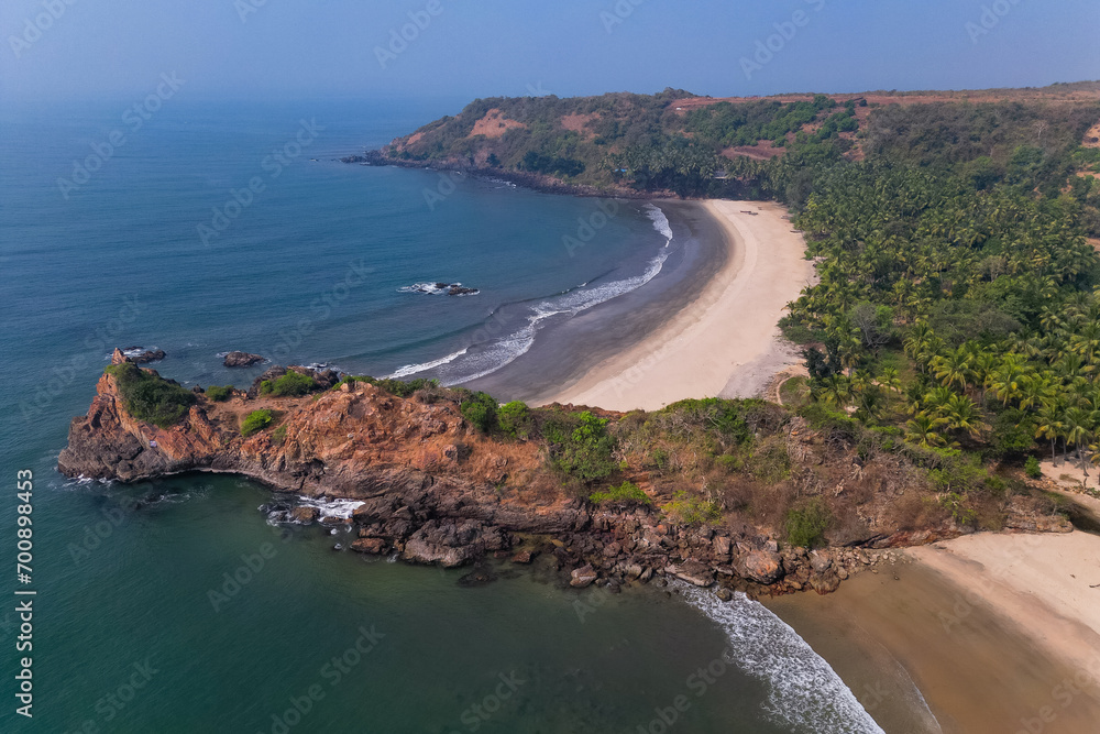Aerial top view on tropical beach with green palm trees under sunlight Drone view in Goa