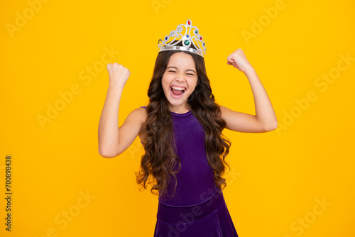Excited face, cheerful emotions of teenager girl. Portrait of ambitious teenage girl with crown, feeling princess, confidence. Child princess crown on isolated studio background.