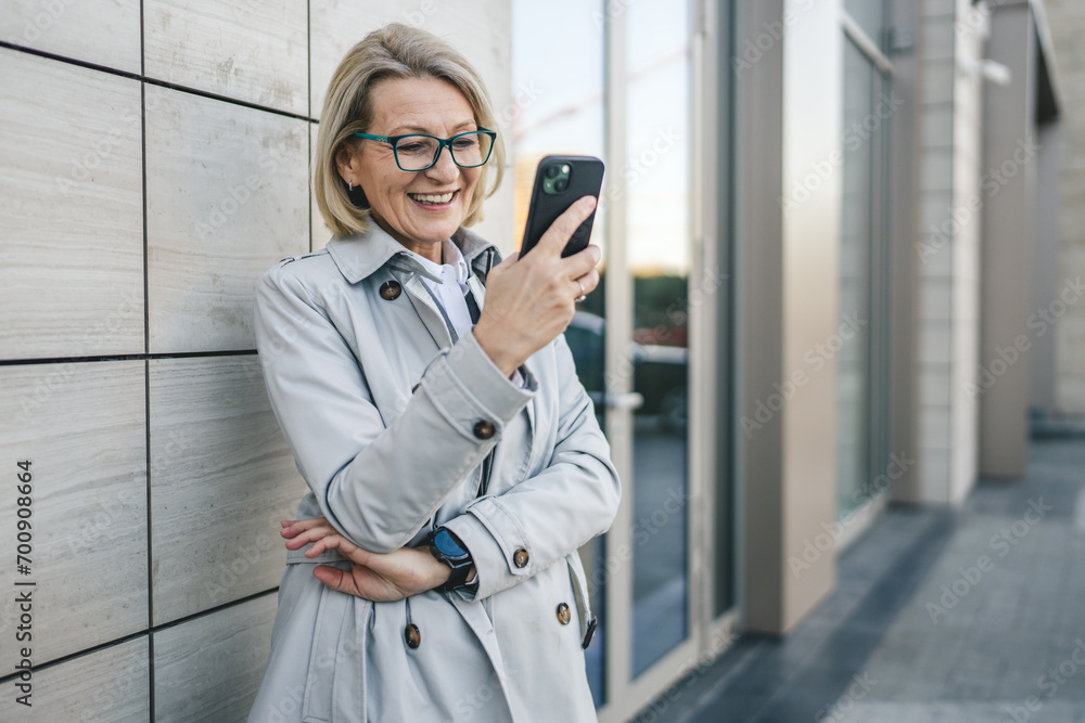 One woman mature female stand in the city outdoor use mobile phone One woman mature female stand in the city outdoor use mobile phone